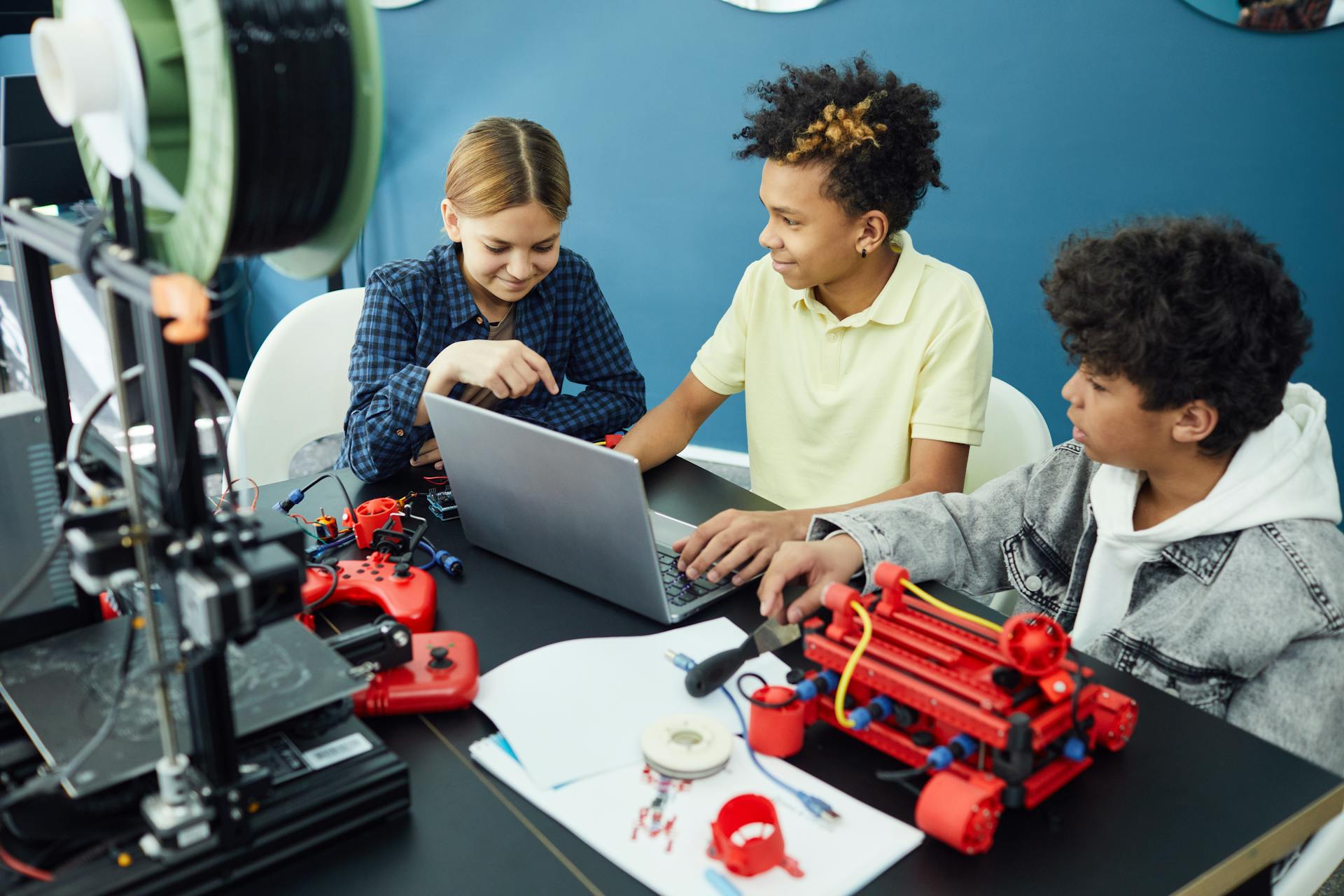 A group of kids working on a 3D printer